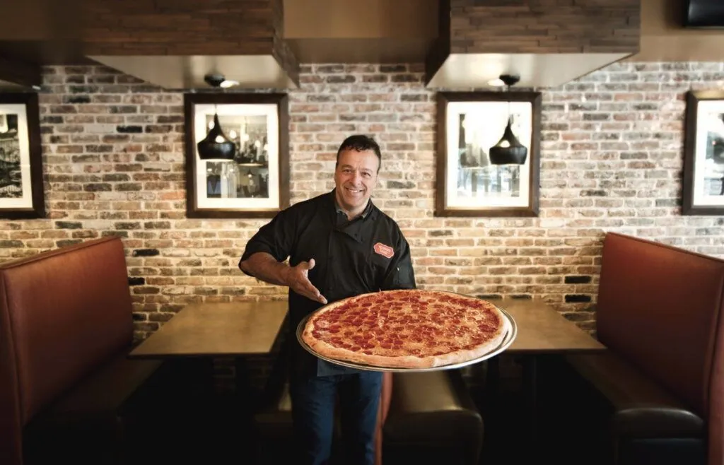 Chef Anthony Russo holding a New York-style pizza